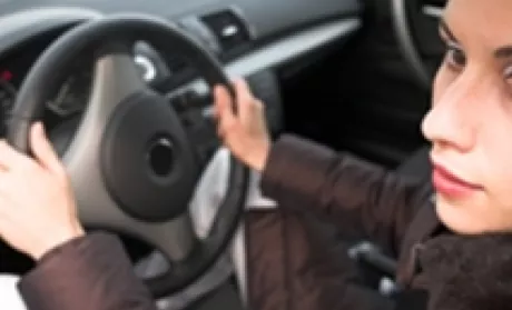 person looking out the driver window while hands are on the wheel.